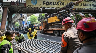 Petugas melakukan proses evakuasi truk bermuatan alat berat yang menabrak jembatan penyeberangan orang (JPO) di Jalan Kapten Tendean, Jakarta, Selasa (14/7/2026). [ANTARA FOTO/Fauzan/nym]
