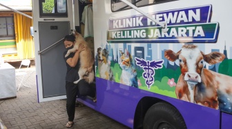Warga membawa hewan peliharaannya usai diperiksa di mobil Klinik Hewan Keliling Jakarta, di Jakarta, Rabu (15/7/2026). [Suara.com/Alfian Winanto]