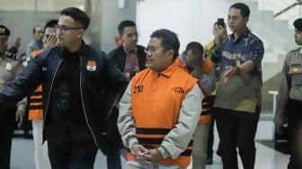 Bupati Lombok Barat Lalu Ahmad Zaini berjalan menuju mobil tahanan usai menjalani pemeriksaan di Gedung Merah Putih KPK, Jakarta, Selasa (21/7/2026). [Suara.com/Alfian Winanto]