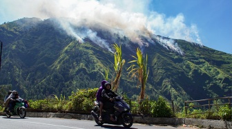 Pengendara melintas dengan latar belakang hutan perbukitan yang terbakar di kawasan Perhutani RPH Sukapura, Blok Gunung Ringgit, Desa Sapikerep, Kecamatan Sukapura, Kabupaten Probolinggo, Jawa Timur, Sabtu (25/7/2026). [ANTARA FOTO/Irfan Sumanjaya/agr]
