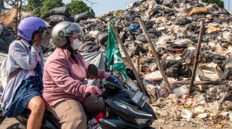 Pengendara sepeda motor melintas di dekat tumpukan sampah di Jalan Kepanduan II, Penjaringan, Jakarta, Senin (27/7/2026). [ANTARA FOTO/Rakha Raditya Yahya/tom]