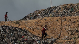 Relawan pemadam kebakaran menarik selang saat melintasi tumpukan sampah di Tempat Pembuangan Akhir (TPA) Rasau Jaya, Kabupaten Kubu Raya, Kalimantan Barat, Kamis (6/8/2026). [ANTARA FOTO/Jessica Wuysang/kye]

