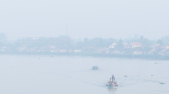 Foto udara sejumlah pelajar berangkat sekolah menggunakan perahu tradisional melewati kawasan yang diselimuti kabut asap di Sungai Ogan, Palembang, Sumatera Selatan, Kamis (13/8/2026). [ANTARA FOTO/Nova Wahyudi/YU]