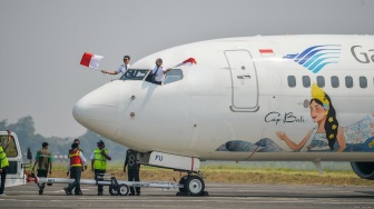 Pilot pesawat Boeing 737-800 milik maskapai Garuda Indonesia mengibarkan bendera Merah Putih saat mendarat di Bandara Husein Sastranegara, Bandung, Jawa Barat, Jumat (14/8/2026). [ANTARA FOTO/Raisan Al Farisi/kye]
