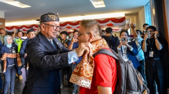 Direktur Utama PT Angkasa Pura Indonesia (Persero) Muhammad Rizal Pahlevi mengalungkan kain kepada penumpang yang baru tiba di Bandara Husein Sastranegara, Bandung, Jawa Barat, Jumat (14/8/2026). [ANTARA FOTO/Raisan Al Farisi/kye]