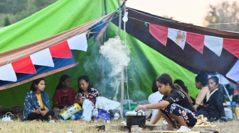 Warga memasak di posko pengungsian korban gempa bumi NTT di Lapangan Barangkolong, Reo, NTT, Senin (17/8/2026). [ANTARA FOTO/Fikri Yusuf/foc]