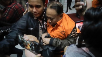 Rektor Universitas Jenderal Soedirman (Unsoed)  bersama tersangka lainnya berjalan menuju mobil tahanan usai menjalani pemeriksaan pasca terjaring operasi tangkap tangan (OTT) di Gedung KPK, Jakarta, Sabtu (22/8/2026) dini hari. [Suara.com/Alfian Winanto]