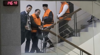Rektor Universitas Jenderal Soedirman (Unsoed)  bersama tersangka lainnya berjalan menuju mobil tahanan usai menjalani pemeriksaan pasca terjaring operasi tangkap tangan (OTT) di Gedung KPK, Jakarta, Sabtu (22/8/2026) dini hari. [Suara.com/Alfian Winanto]