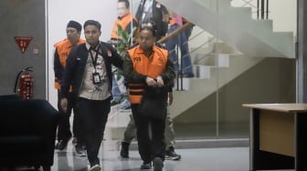Rektor Universitas Jenderal Soedirman (Unsoed)  bersama tersangka lainnya berjalan menuju mobil tahanan usai menjalani pemeriksaan pasca terjaring operasi tangkap tangan (OTT) di Gedung KPK, Jakarta, Sabtu (22/8/2026) dini hari. [Suara.com/Alfian Winanto]