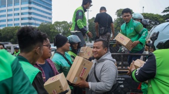 Pengemudi ojek online (ojol) membantu memindahkan logistik di depan Gedung DPR RI, Jakarta, Rabu (26/8/2026). [Suara.com/Alfian Winanto]
