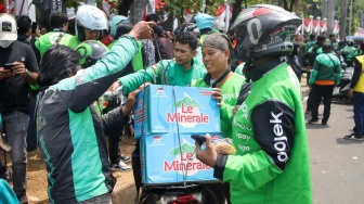 Pengemudi ojek online (ojol) membantu memindahkan logistik di depan Gedung DPR RI, Jakarta, Rabu (26/8/2026). [Suara.com/Alfian Winanto]
