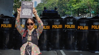 Salah seorang peserta demo menampilkan posternya saat menggelar aksi di depan Gedung DPR RI, Jakarta, Kamis (28/8/2026). [Suara.com/Alfian Winanto]