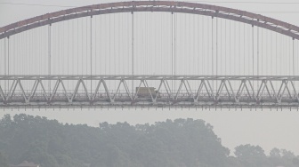 Kendaraan melintas di Jembatan Kahayan yang diselimuti asap dampak kebakaran hutan dan lahan di Palangka Raya, Kalimantan Tengah, Jumat (28/8/2026). [ANTARA FOTO/Auliya Rahman/nym]