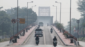 Pengendara melintas di Jembatan Kahayan yang diselimuti asap dampak kebakaran hutan dan lahan di Palangka Raya, Kalimantan Tengah, Jumat (28/8/2026). [ANTARA FOTO/Auliya Rahman/nym]