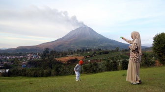 Wisatawan bermain bersama anaknya saat erupsi Gunung Sinabung di Desa Kutarayat, Kecamatan Naman Teran, Kabupaten Karo, Sumatera Utara, Selasa (1/9/2026). [ANTARA FOTO/Yudi Manar/YU]