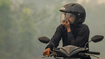 Pengendara sepeda motor melintas di Jalan Gubernur Syarkawi yang tertutup kabut asap akibat kebakaran hutan dan lahan (karhutla) di Kabupaten Banjar, Kalimantan Selatan, Rabu (2/9/2026). [ANTARA FOTO/Bayu Pratama S/nym]