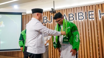Dudy Purwagandhi, Menteri Perhubungan Republik Indonesia (Kiri) menyapa salah satu perwakilan Mitra Pengemudi dalam prosesi keberangkatan 105 Mitra Pengemudi Grab program Berangkat Umrah (BERKAH) di Jakarta, Jumat (11/9). [handout]