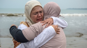 Istri Arie Basuki, Yanti (kanan) berpelukan dengan kakak dari Arie Basuki, Dewi saat melakukan tabur bunga di pantai Pagedongan, Pandeglang, Banten, Jumat (18/9/2026). [ANTARA FOTO/Paramayuda/agr]