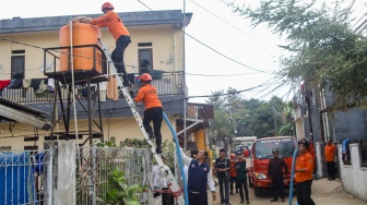 Personel BPBD Jakarta Selatan mengisi air ke dalam wadah milik warga yang terdampak kekeringan di Lenteng Agung, Jakarta, Jumat (18/9/2026). [Suara.com/Alfian Winanto]