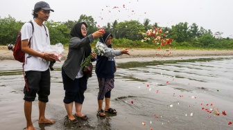 Istri dan ibu jurnalis ANTARA yang hilang kontak, M Bagus Khoirunas, Desi Purnama Sari (kiri), Tini (tengah) dan Korlip Antara Foto Sigid Kurniawan (kiri) berdoa usai melakukan tabur bunga di bibir Pantai Kampung Pagedongan, Carita, Pandeglang, Banten, Jumat (18/9/2026). [ANTARA FOTO/Angga Budhiyanto/agr]