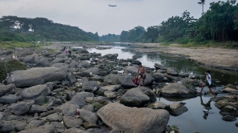 Dua anak berjalan di antara bebatuan Sungai Cisadane di Kota Tangerang, Banten, Jumat (18/9/2026). [ANTARA FOTO/Putra M. Akbar/wpa]