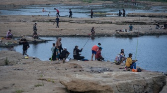 Warga memancing ikan di Sungai Cisadane yang airnya surut di Kota Tangerang, Banten, Jumat (18/9/2026). [ANTARA FOTO/Putra M. Akbar/wpa]