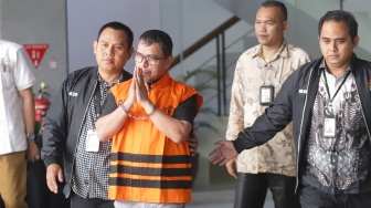 Bupati Bolaang Mongondow Utara, Sirajudin Lasena (tengah) mengenakan rompi tahanan berjalan menuju mobil tahanan usai menjalani pemeriksaan di Gedung Merah Putih KPK, Jakarta, Selasa (22/9/2026). [Suara.com/Alfian Winanto]