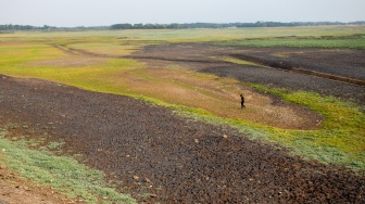 Warga berlajan di dasar Waduk Cipancuh yang mengering di Haurgeulis, Indramayu, Jawa Barat, Minggu (27/9/2026). [ANTARA FOTO/Dedi Suwidiantoro/sgd]