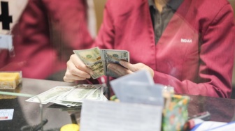Petugas salah satu tempat penukaran mata uang asing menghitung uang rupiah dan dollar AS di Jakarta, Selasa (29/9/2026). [Suara.com/Alfian Winanto]