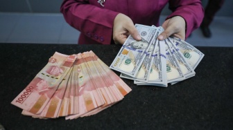 Petugas salah satu tempat penukaran mata uang asing menunjukkan uang rupiah dan dollar AS di Jakarta, Selasa (29/9/2026). [Suara.com/Alfian Winanto]