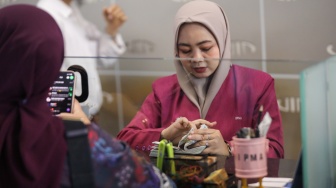 Petugas melayani penukaran uang asing di Jakarta, Selasa (29/9/2026). [Suara.com/Alfian Winanto]