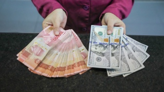 Petugas salah satu tempat penukaran mata uang asing menunjukkan uang rupiah dan dollar AS di Jakarta, Selasa (29/9/2026). [Suara.com/Alfian Winanto]