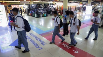 Pengguna transportasi umum berjalan mengikuti penunjuk arah (wayfinding) di area Terminal Blok M, Jakarta Selatan, Rabu (30/9/2026). [Suara.com/Alfian Winanto]