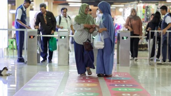 Pengguna transportasi umum berjalan mengikuti penunjuk arah (wayfinding) di area Terminal Blok M, Jakarta Selatan, Rabu (30/9/2026). [Suara.com/Alfian Winanto]