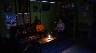 Warga berbincang dengan penerangan lilin di dalam rumahnya yang belum mendapatkan layanan listrik di Dusun Suka Jaya, Desa Lagan Ulu, Tanjung Jabung Timur, Jambi, Rabu (7/10/2026). [ANTARA FOTO/Wahdi Septiawan/wsj]
