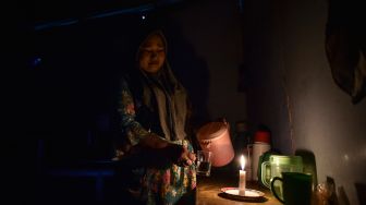 Seorang warga menuangkan air ke dalam gelas dengan penerangan lilin di dalam rumahnya yang belum mendapatkan layanan listrik di Dusun Suka Jaya, Desa Lagan Ulu, Tanjung Jabung Timur, Jambi, Rabu (7/10/2026). [ANTARA FOTO/Wahdi Septiawan/wsj]