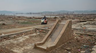 Pengendara roda dua melintas di samping taman bermain yang muncul kembalu di tepian Waduk Jatigede yang surut di Desa Cipaku, Kecamatan Darmaraja, Kabupaten Sumedang, Jawa Barat, Minggu (11/10/2026). [ANTARA FOTO/Raisan Al Farisi/bar]

