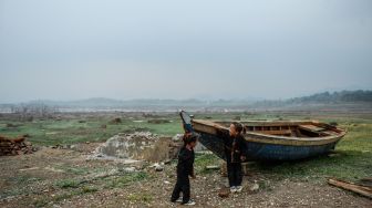 Dua orang anak bermain diantara perahu yang karam di tepian Waduk Jatigede yang surut di Desa Cipaku, Kecamatan Darmaraja, Kabupaten Sumedang, Jawa Barat, Minggu (11/10/2026). [ANTARA FOTO/Raisan Al Farisi/bar]