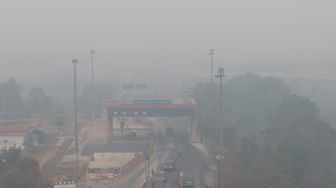 Sejumlah kendaraan mengantre untuk melintasi Gerbang Tol Kramasan di Jalan Tol Trans-Sumatera (JTTS) ruas Palembang-Lampung yang tertutup kabut asap di Desa Ibul Besar III, Pemulutan, Ogan Ilir, Sumatera Selatan, Selasa (13/10/2026). [ANTARA FOTO/Nova Wahyudi/tom]
