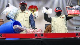 Petugas menunjukan barang bukti dari dalam tong dari kasus OTT Bupati Klaten Hamenang Wajar Ismoyo saat konferensi pers di Gedung Merah Putih KPK, Jakarta, Jumat (16/10/2026). [Suara.com/Alfian Winanto]
