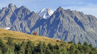 Pemandangan Pegunungan Kaukasus dengan hamparan perbukitan dan dua pondok kayu di kawasan Svaneti, Georgia, Minggu (27/9/2026). [Suara.com/Rizka Chaerani]