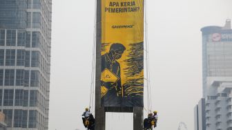 Sejumlah aktifis Greenpeace membentangkan spanduk yang bertema krisis iklim di Bundaran HI, Jakarta, Selasa (20/10/2026). [Suara.com/Alfian Winanto]
