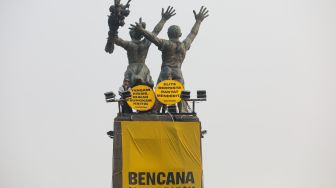 Sejumlah aktifis Greenpeace membentangkan spanduk yang bertema krisis iklim di Bundaran HI, Jakarta, Selasa (20/10/2026). [Suara.com/Alfian Winanto]
