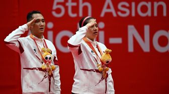 Pebulu tangkis ganda campuran Indonesia Hikmat Ramdani (kiri) dan Leani Ratri Oktila (kanan) memberi hormat bendera Merah Putih saat upacara medali seusai mengalahkan pasangan India Thulasimathi Murugesan dan Nitesh Kumar pada final ganda campuran SL3-SU5 Asian Para Games 2026 di Municipal Gymnasium, Ichinomiya, Nagoya, Jepang, Jumat (23/10/2026). [ANTARA FOTO/M Risyal Hidayat/nz]