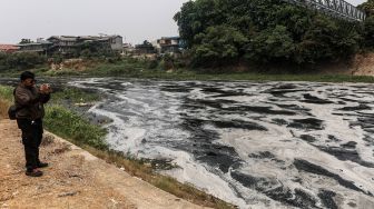 Warga merekam aliran Kali Bekasi yang berbusa dan berwarna hitam, diduga akibat pencemaran limbah, di kawasan Margahayu, Kota Bekasi, Jawa Barat, Jumat (23/10/2026). [ANTARA FOTO/Darryl Ramadhan/kye]
