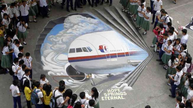 Sejumlah siswa berkumpul dekat karya seni tiga dimensi pesawat Malaysia Airlines MH370, di Makati City, Manila, Senin (17/3). [Reuters/Romeo Ranoco ]