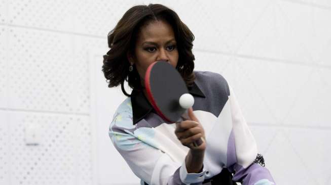 Michelle Obama bermain tenis meja saat berkunjung ke sebuah sekolah di Beijing, Jumat 21/3). [Reuters/Andy Wong]