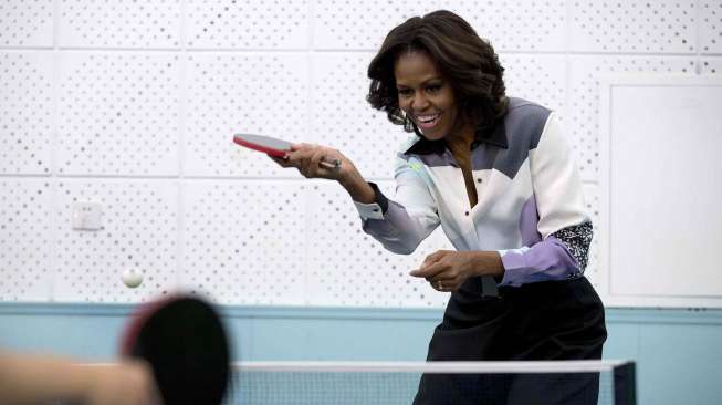 Michelle Obama bermain tenis meja saat berkunjung ke sebuah sekolah di Beijing, Jumat (21/3). [Reuters/Andy Wong]