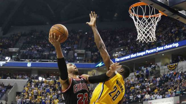 Pebasket Indiana Pacers Ian Mahinmi (kanan) berusaha merebut bola dari pebasket Chicago Bulls Joakim Noah dalam pertandingan di Bankers Life Fieldhouse, Jumat (21/3). [Reuters/Brian Spurlock]
