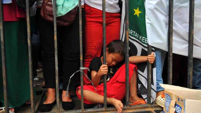 Seorang bocah tertidur saat kampanye terbuka Partai Kebangkitan Bangsa di Lapangan Pacuan Kuda Pulomas, Jakarta, Senin (24/3). [suara.com/Adrian Mahakam]